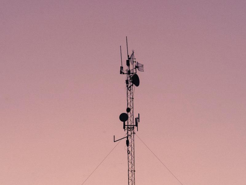 Telecom mast with microwave dishes at dusk
