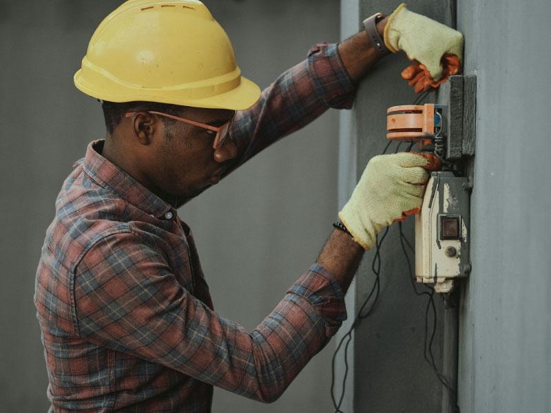 Electrician wiring a wall-mounted meter box